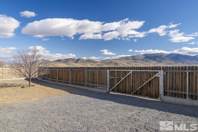 view of yard featuring a gate, a mountain view, and fence