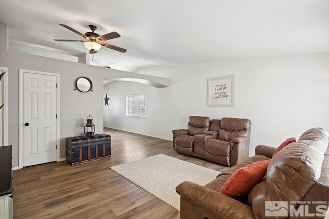 living room with ceiling fan, arched walkways, vaulted ceiling, and wood finished floors