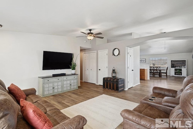 living area with a ceiling fan, lofted ceiling, baseboards, and wood finished floors