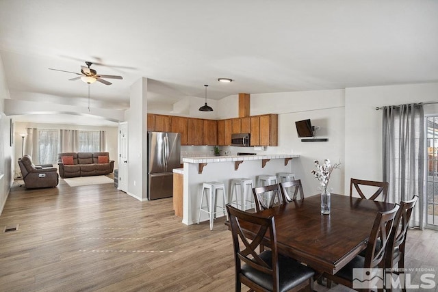 dining room with a ceiling fan, a wealth of natural light, visible vents, and light wood finished floors