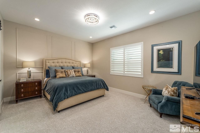 bedroom with recessed lighting, light colored carpet, visible vents, a decorative wall, and baseboards