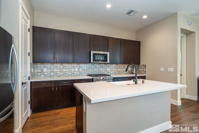 kitchen with visible vents, light countertops, appliances with stainless steel finishes, decorative backsplash, and dark wood-style floors