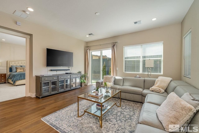 living area with wood finished floors, visible vents, and recessed lighting