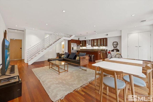 living area featuring stairs, visible vents, wood finished floors, and recessed lighting