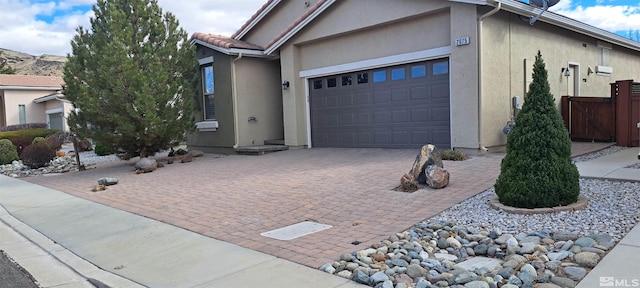 single story home featuring a garage, driveway, a tiled roof, and stucco siding