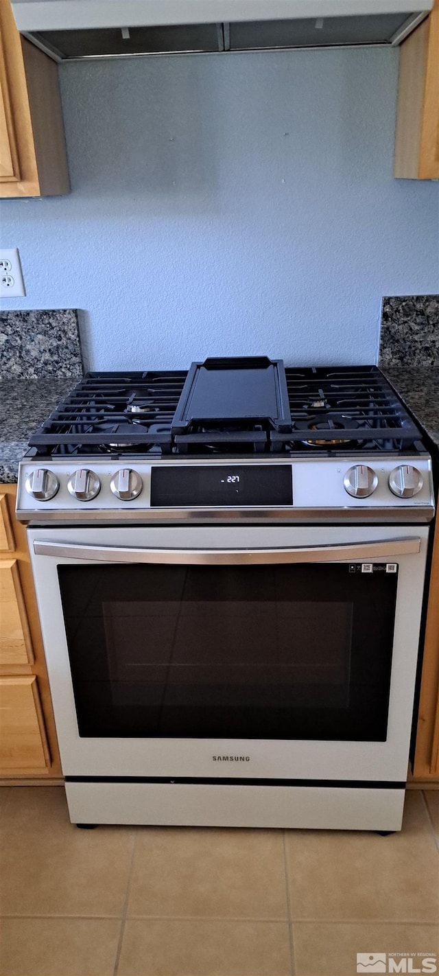 kitchen featuring dark countertops, stainless steel range with gas stovetop, and light tile patterned floors