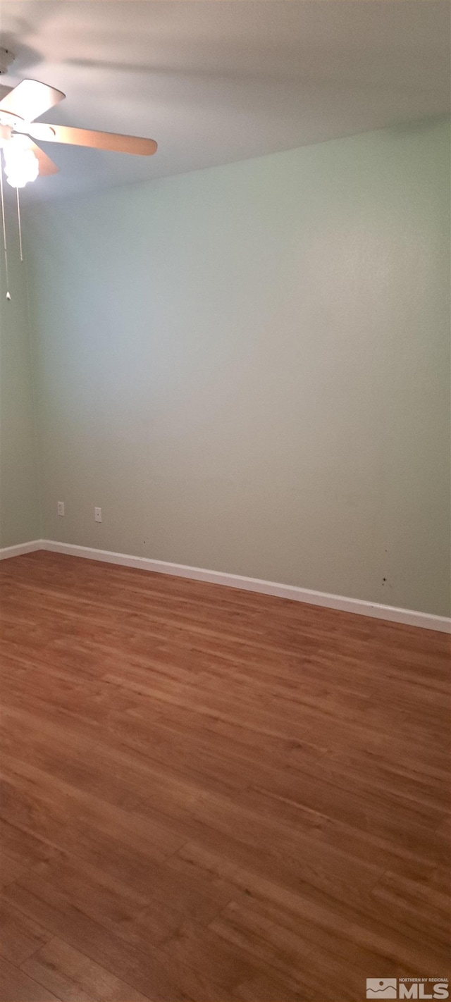 spare room featuring ceiling fan, wood finished floors, and baseboards