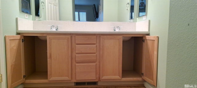 bathroom featuring a textured wall, a sink, and visible vents