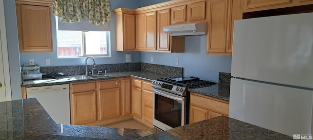 kitchen featuring dark stone counters, white appliances, a sink, and under cabinet range hood