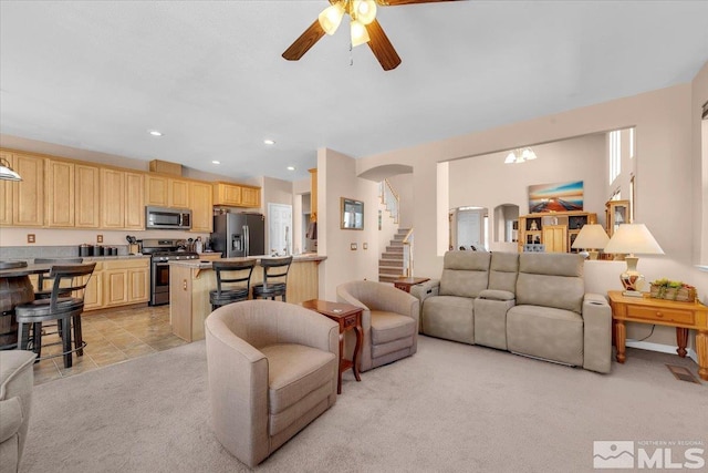 living room with arched walkways, ceiling fan, recessed lighting, light colored carpet, and stairway