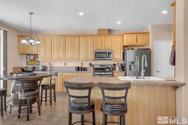 kitchen with recessed lighting, appliances with stainless steel finishes, a kitchen breakfast bar, and light brown cabinetry