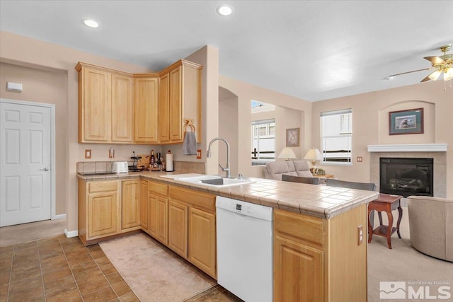 kitchen featuring a peninsula, a sink, open floor plan, dishwasher, and light brown cabinetry