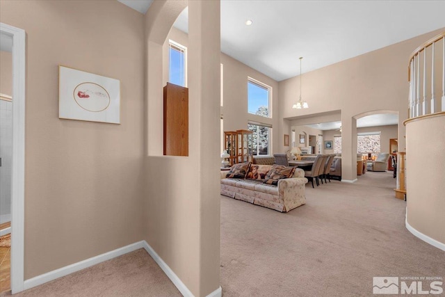 interior space with arched walkways, a chandelier, a towering ceiling, and baseboards