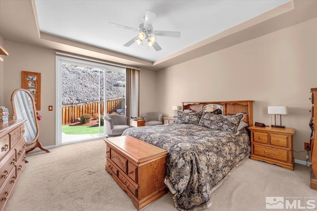 bedroom featuring baseboards, access to outside, a tray ceiling, and light colored carpet