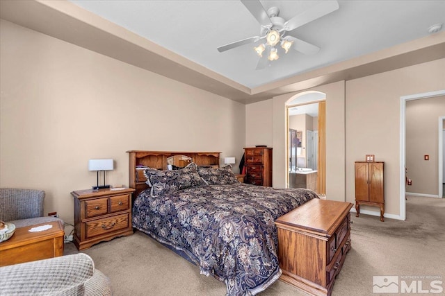 bedroom with light carpet, ensuite bath, ceiling fan, and baseboards