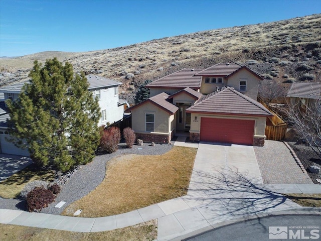 view of front of house with a garage, a tile roof, driveway, stone siding, and stucco siding