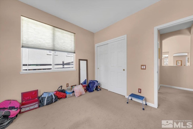 bedroom featuring carpet floors, baseboards, arched walkways, and a closet