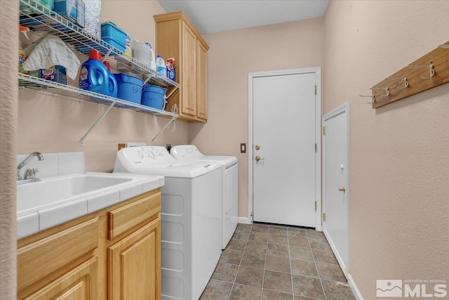 laundry area featuring baseboards, cabinet space, a sink, and washing machine and clothes dryer