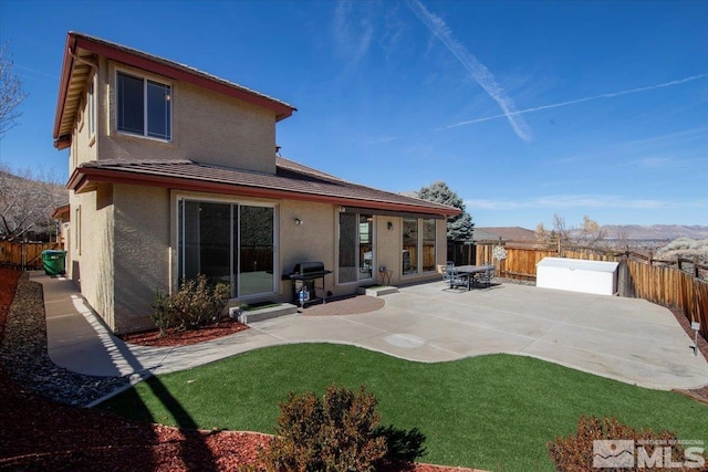 back of house with a patio, a lawn, a fenced backyard, and stucco siding