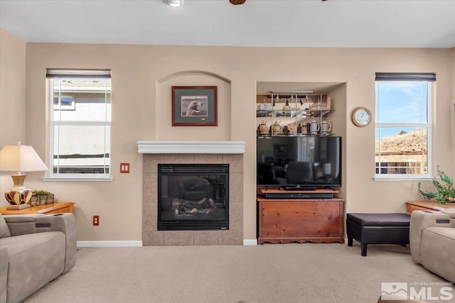 living room with carpet floors, baseboards, and a tiled fireplace