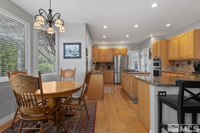 kitchen featuring stainless steel appliances, recessed lighting, backsplash, a kitchen island, and light wood-type flooring