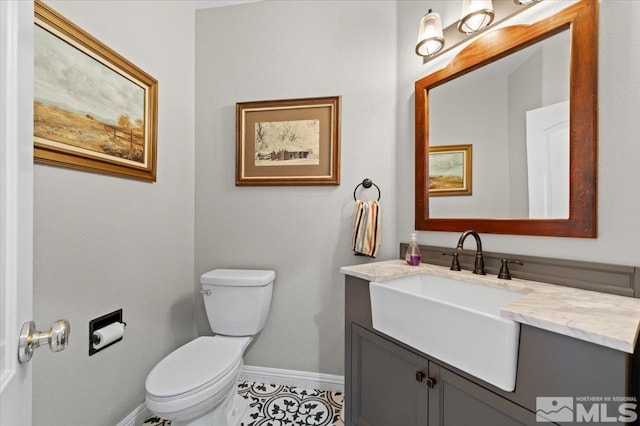 half bath with vanity, toilet, and baseboards