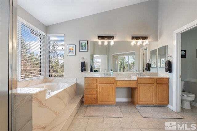 bathroom with toilet, vaulted ceiling, a bath, tile patterned floors, and double vanity