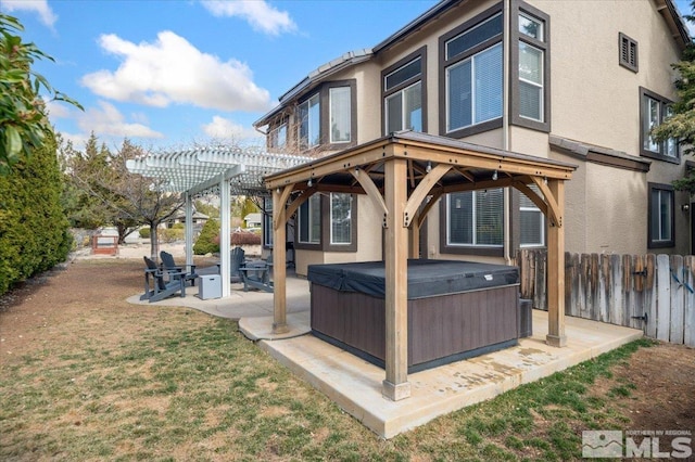 rear view of house with a patio, stucco siding, a hot tub, fence, and a pergola