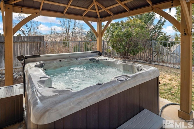 view of patio / terrace with fence, a hot tub, and a gazebo