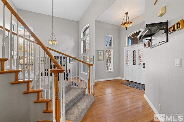 entryway with a towering ceiling, a wealth of natural light, baseboards, and wood finished floors