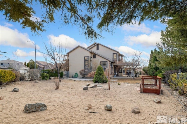 view of front of property featuring a garden, fence, a patio, and stucco siding