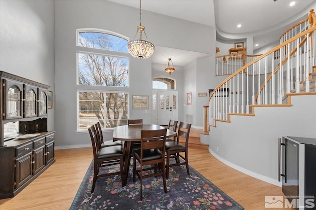 dining room featuring a high ceiling, plenty of natural light, stairway, and light wood finished floors