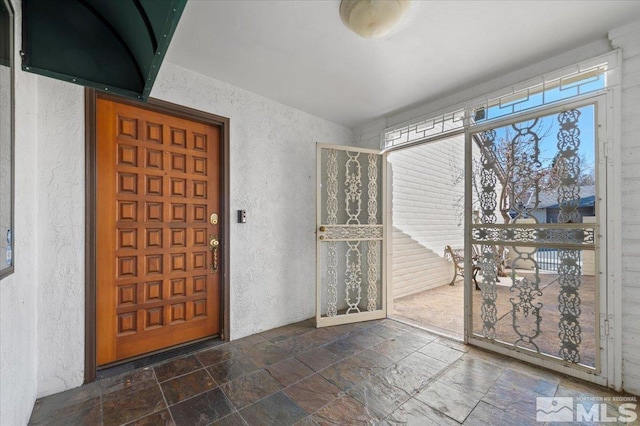 interior space with stone tile floors and a textured wall