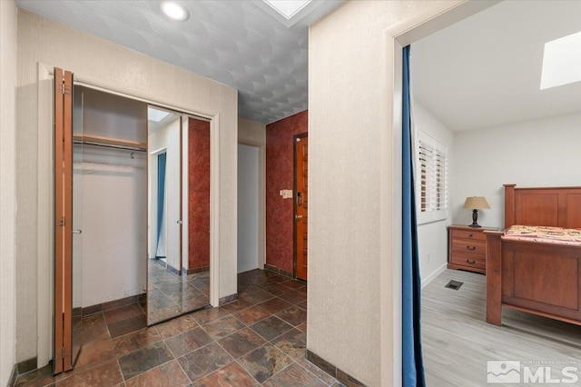 bedroom with a skylight, a closet, visible vents, and stone finish flooring