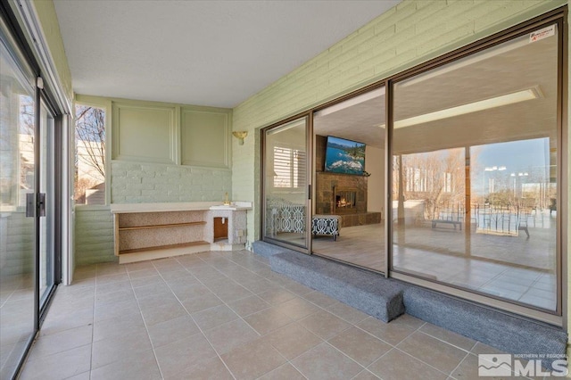 unfurnished sunroom with a lit fireplace