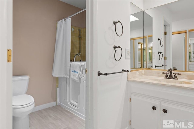 bathroom featuring curtained shower, toilet, vanity, wood finished floors, and baseboards