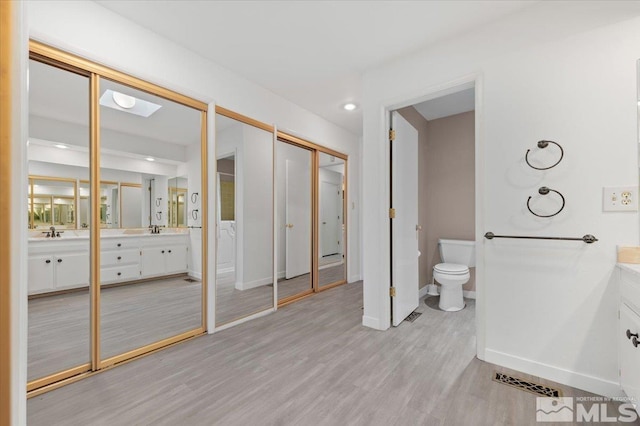 full bath with toilet, wood finished floors, vanity, and baseboards