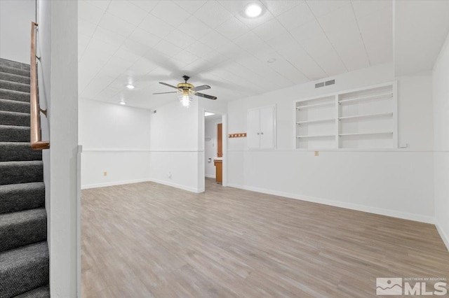 unfurnished living room with light wood finished floors, visible vents, ceiling fan, baseboards, and stairs