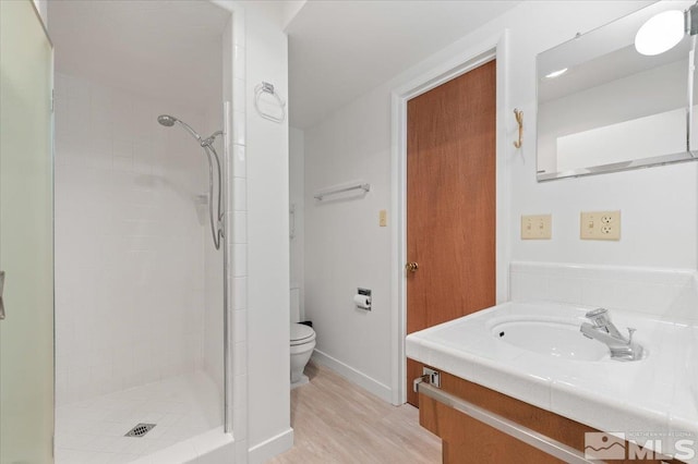 bathroom featuring toilet, a shower stall, wood finished floors, and vanity