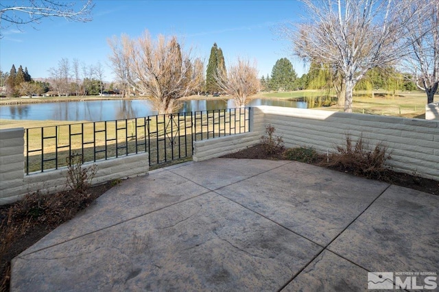 view of patio with a water view and fence