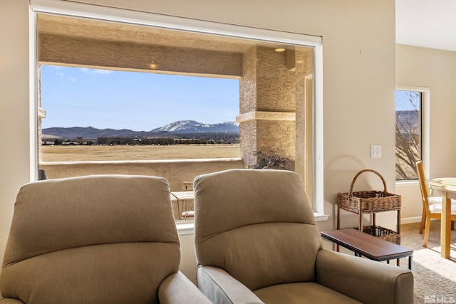 living area featuring carpet flooring, a mountain view, and baseboards