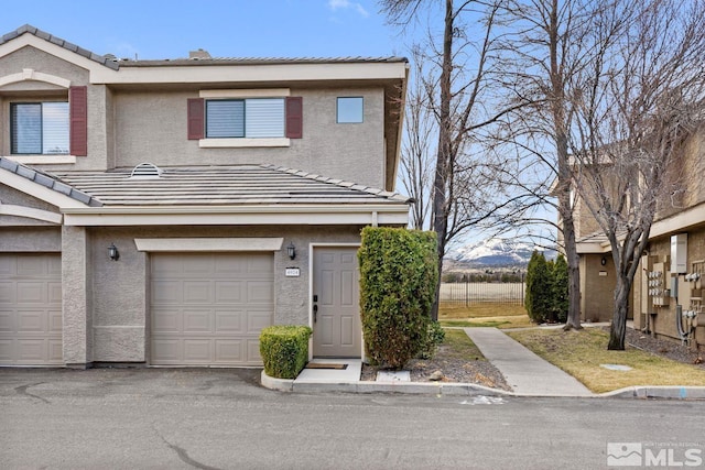 multi unit property with a garage, a tile roof, and stucco siding