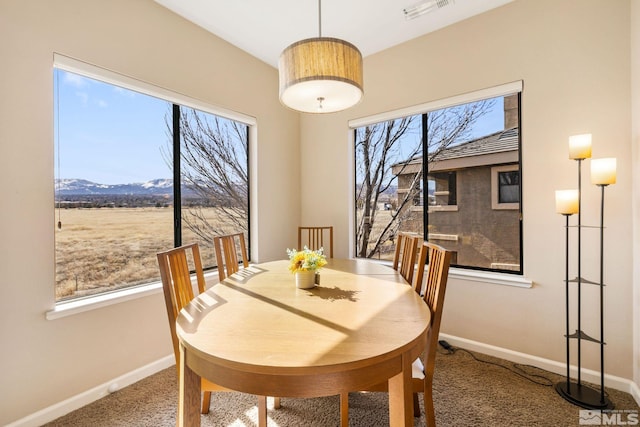 carpeted dining area with a healthy amount of sunlight, visible vents, and baseboards