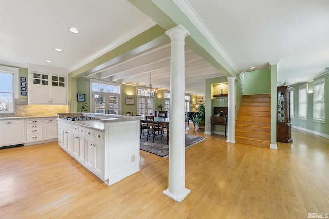 kitchen with plenty of natural light, light wood-type flooring, white cabinetry, and ornate columns