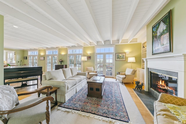 living area featuring wood finished floors, french doors, beamed ceiling, and a fireplace with flush hearth