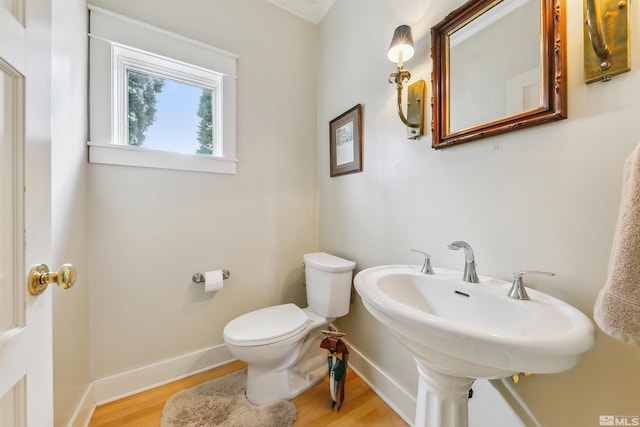 half bath with baseboards, toilet, and wood finished floors