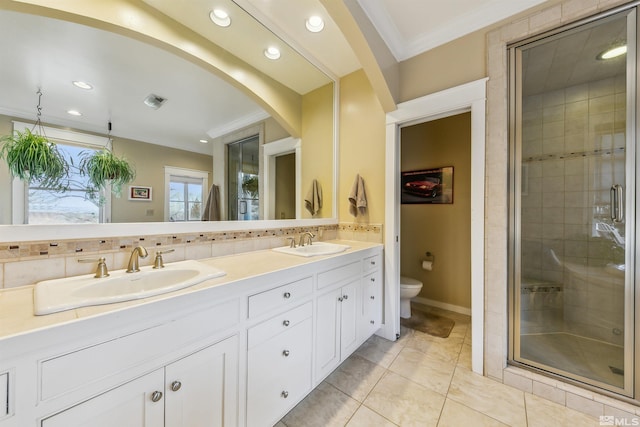 bathroom featuring ornamental molding, a stall shower, a sink, and toilet