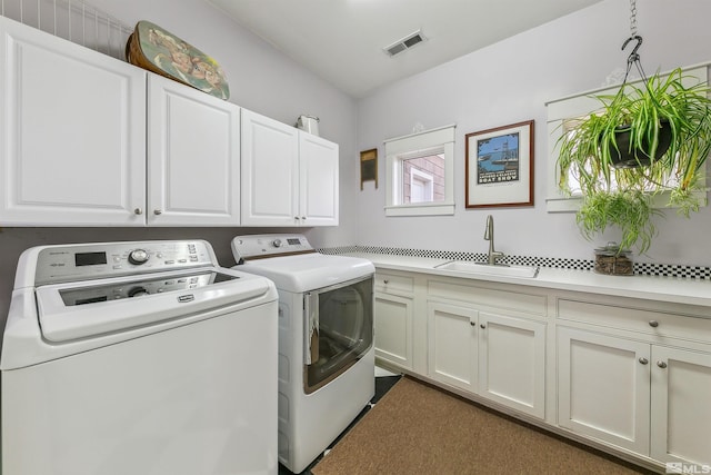 laundry area featuring cabinet space, visible vents, a sink, and washing machine and clothes dryer