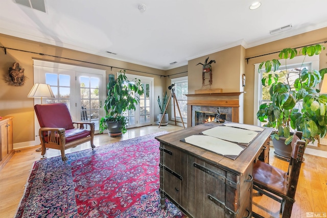 living room with ornamental molding, a premium fireplace, light wood-type flooring, and visible vents