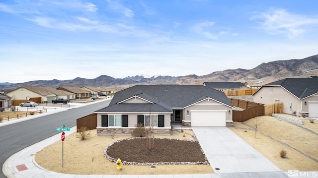 view of front of house with an attached garage, a mountain view, fence, concrete driveway, and a residential view